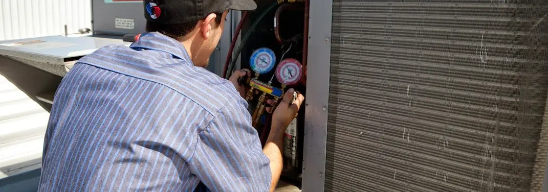 HVAC technician servicing a condenser unit in Marysville